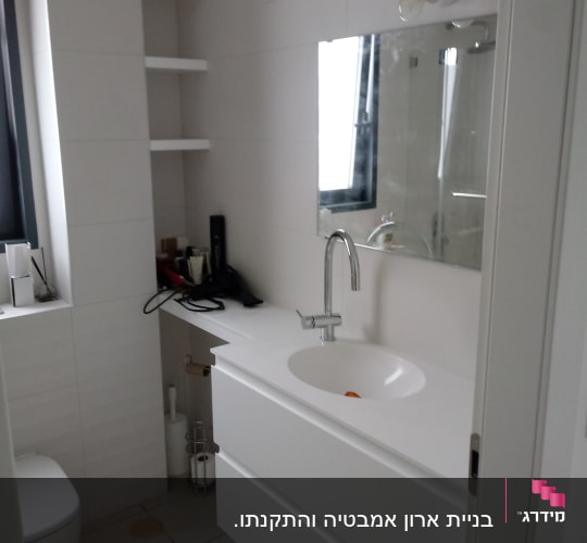 חדר אמבטיה עם כיור ומראה, מדפים ריקים